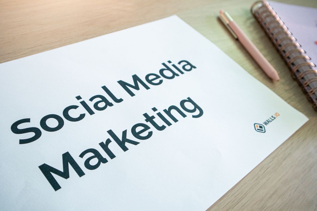 services-03 Gros plan sur un document de marketing sur les réseaux sociaux posé sur un bureau, avec un stylo et un carnet.